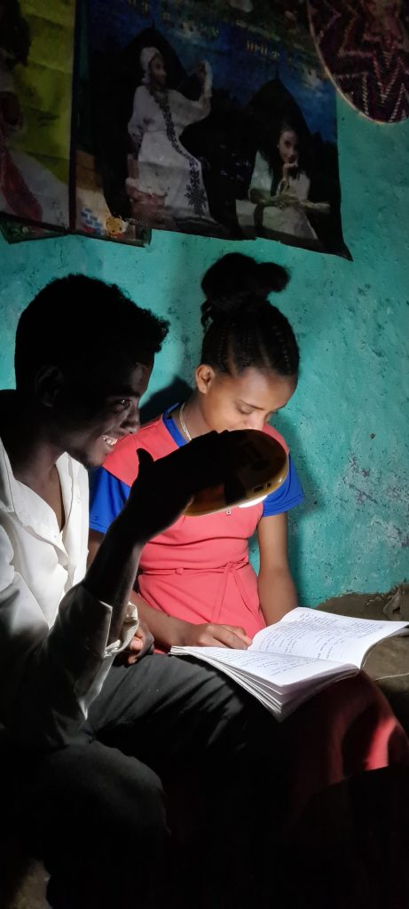 Two young people doing homework under a solar light